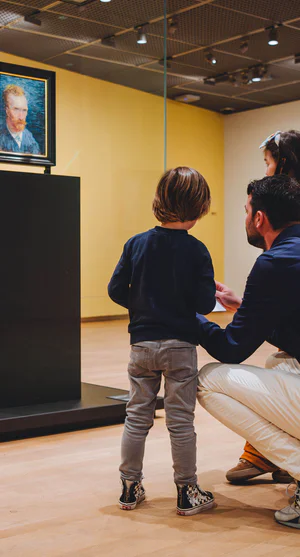 Een vader kijkt met zijn zoontje en dochter naar een zelfportret van Vincent van Gogh in het Van Gogh Museum. Foto: Jelle Draper