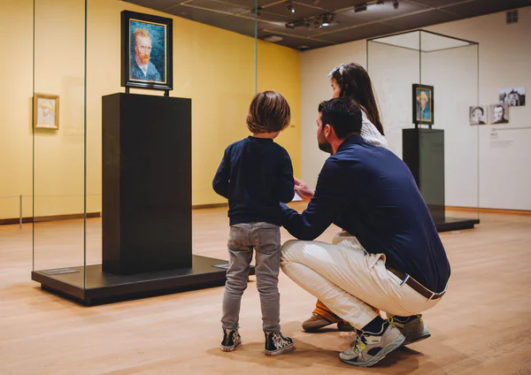 Een vader kijkt met zijn zoontje en dochter naar een zelfportret van Vincent van Gogh in het Van Gogh Museum. Foto: Jelle Draper