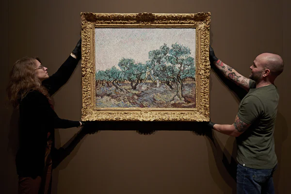 Twee museummedewerkers hangen een schilderij aan de muur in de tentoonstelling 'Van Gogh en de olijfgaarden'. Van Gogh Museum, Amsterdam (Foto: Michael Floor)
