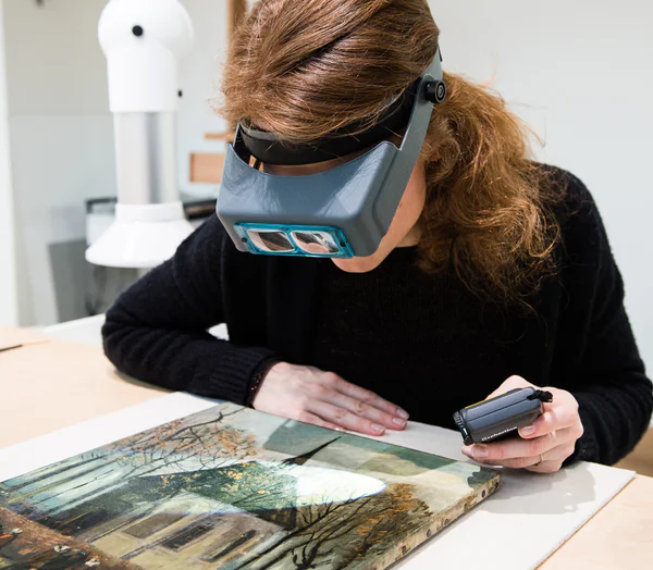Een restaurator onderzoekt Van Goghs schilderij van de uitgaande kerk te Nuenen. Foto: Maartje Strijbis