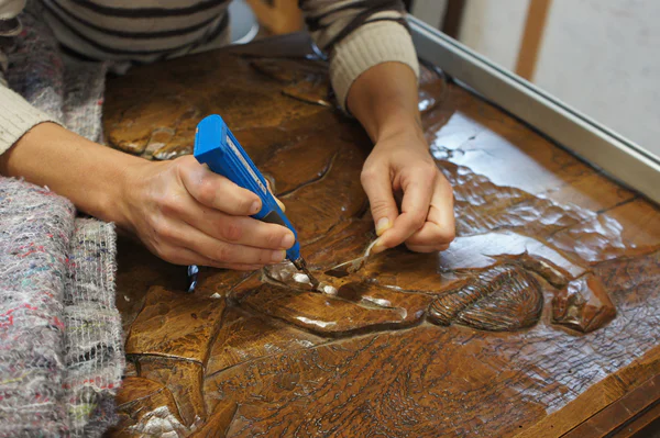 De restaurator vult de naden van het reliëf Bretonse dans van Georges Lacombe met was (foto: Jan Paul Folkers)