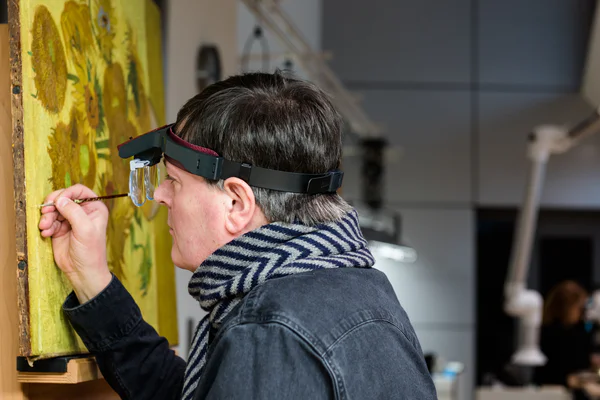 Senior Restaurator René Boitelle restaureert het schilderij Zonnebloemen van Vincent van Gogh. Foto: Maartje Strijbis