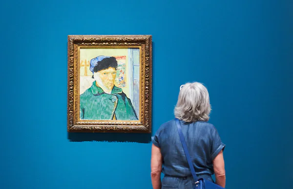 Een vrouw kijkt naar Van Goghs Zelfportret met verbonden oor in de tentoonstelling In the Picture, foto Tomek Dersu Aaron