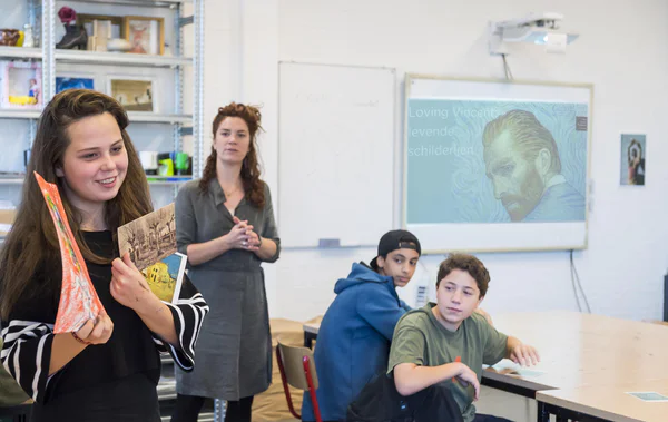 Een leerlinge laat een aantal kaarten met werken van Vincent van Gogh zien aan de andere leerlingen in haar klas. Foto: Jan-Kees Steenman