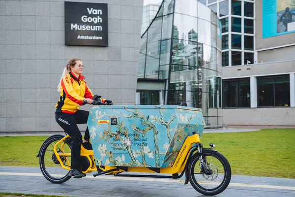 DHL pakketbezorger met haar bakfiets op het Museumplein voor het Van Gogh Museum. Foto: Jelle draper