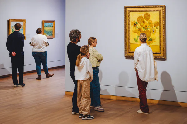 Een gezin krijgt uitleg bij het schilderij Zonnebloemen van Vincent van Gogh tijdens een rondleiding in het Van Gogh Museum. Foto: Jelle Draper